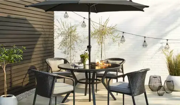 White outdoor dining set positioned near garden wall